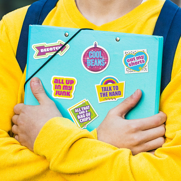 Person holding a turquoise folder with colorful stickers, wearing a yellow shirt and blue backpack. Retro 90s stickers with slang expressions are positioned on binder.