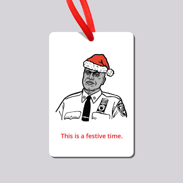 A rectangular white Christmas ornament hanging from a red ribbon, featuring a black-and-white illustration of Brooklyn Nine Nine's Captain Holt wearing a red Santa hat, with the red text 'This is a festive time.' 