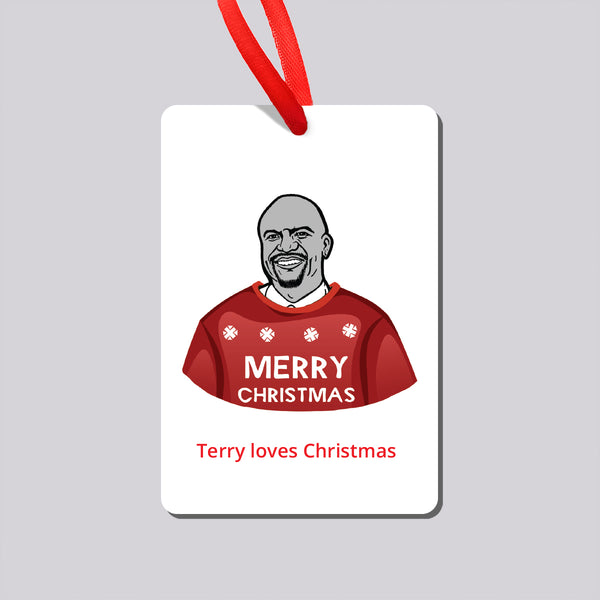 A Christmas ornament hanging from a red ribbon, featuring an illustration of Brooklyn Nine Nine's Terry wearing a red sweater with snowflakes and the words 'MERRY CHRISTMAS'. Below the illustration, the text reads 'Terry loves Christmas'. 