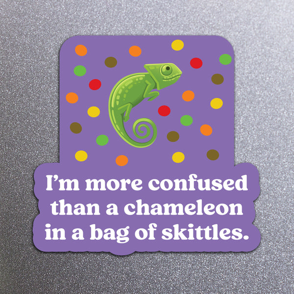 Sticker with a chameleon on a purple background with colorful skittles and text that says 'I'm more confused than a chameleon in a bag of skittles.'