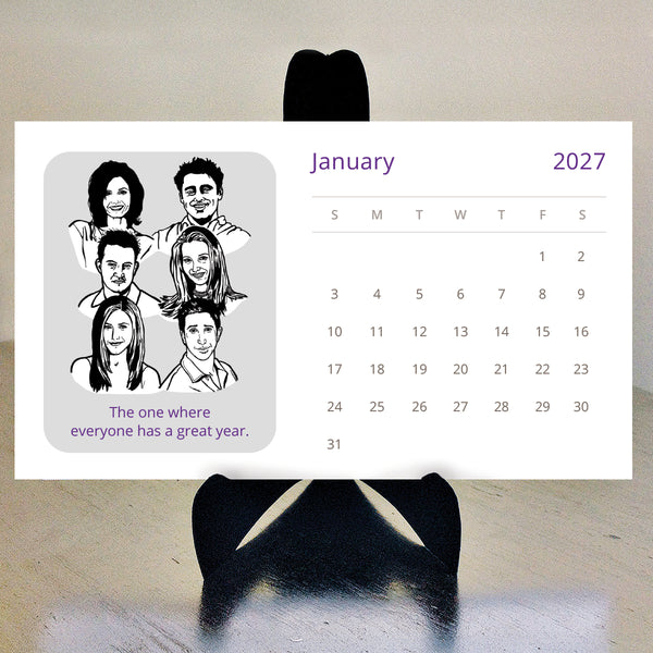 A desk calendar for 2027 featuring black and white illustrations of the Friends tv show characters on a black stand.