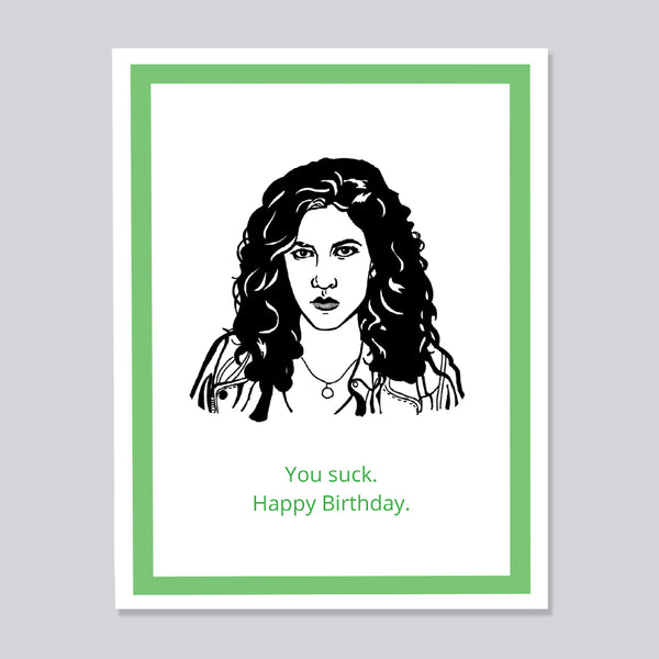 A greeting card featuring a black and white line art portrait of Brooklyn Nine Nine's Rosa bordered by a green inner frame and a white outer border. Below the portrait, the text reads 'You suck. Happy Birthday.'