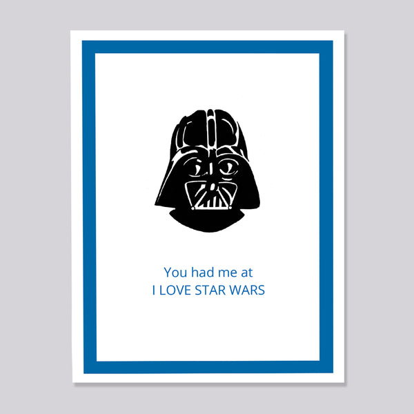 A greeting card featuring a black illustration of Darth Vader above blue text that reads 'You had me at I LOVE STAR WARS', set within a blue border on a white background, shown against a light gray backdrop.