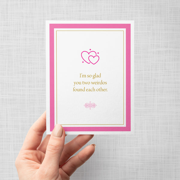 Hand holding greeting card with pink hearts and text 'I'm so glad you two weirdos found each other'
