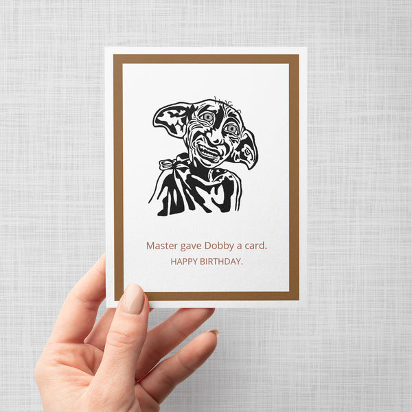hand holding an illustration of dobby from harry potter on a greeting card with text 'master gave dobby a card. happy birthday.'