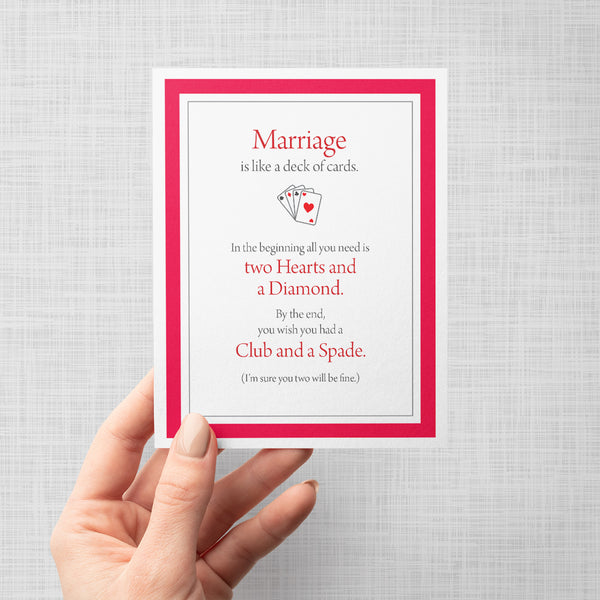 Hand holding a greeting card with text 'Marriage is like a deck of cards. In the beginning all you need is to hearts and a diamond. By the end, you wish you had a club and a space. I'm sure you two will be fine'