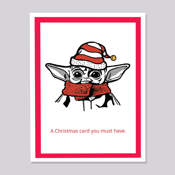 A Christmas-themed greeting card featuring a cartoon illustration of Grogu wearing a red and white Santa hat and matching red scarf, with the text 'A Christmas card you must have.' printed below.