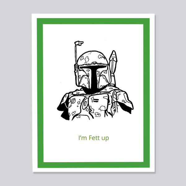 A greeting card featuring a black line art illustration of Boba Fett from Star Wars, with the text 'I'm Fett up' printed in green below. The card is framed with a white border and a green inner border, set against a solid gray background.