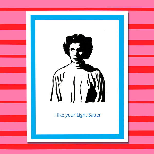 A greeting card featuring a black illustration of a Princess Leia with a light saber, bordered by a blue frame on a white background, with the text 'I like your Light Saber' printed in blue at the bottom on a red and pink striped background.