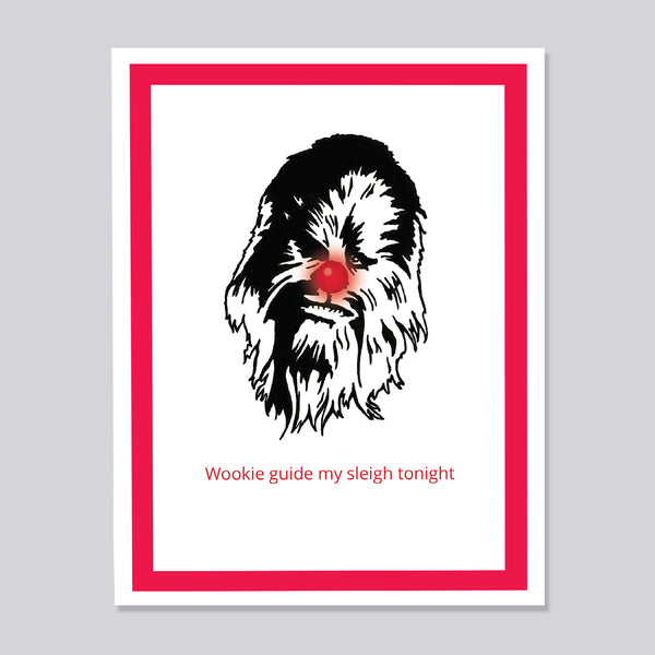 A greeting card featuring a black line-art illustration of Chewbacca's face with the red text 'Wookie guide my sleigh tonight' underneath, framed by a bold red border on a white background, shown against a light gray backdrop.