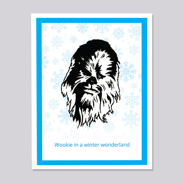 A greeting card featuring a black-and-white illustration of Chewbacca centered on a white background with light blue snowflakes, framed by a bright blue border. The text 'Wookie in a winter wonderland' appears in blue at the bottom.
