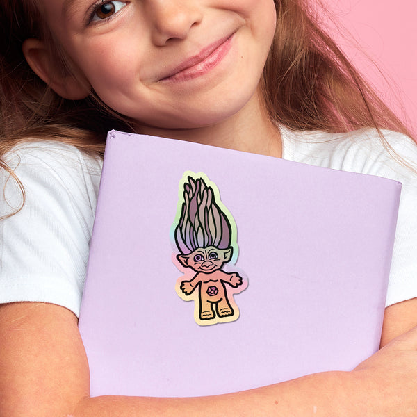 Child holding a purple notebook with a colorful troll doll sticker on a holographic background.